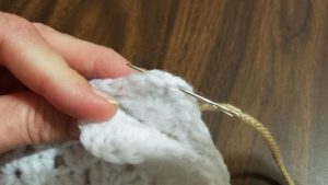 Insert needle just into and through top of stitch on back square at corner chain space as seen in image above.